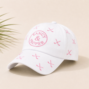 White cap with pink branding and patterns on a beige background