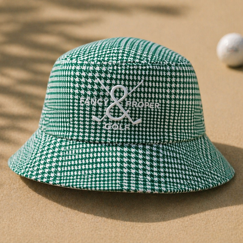 Green checkered bucket hat with branding on a sandy background