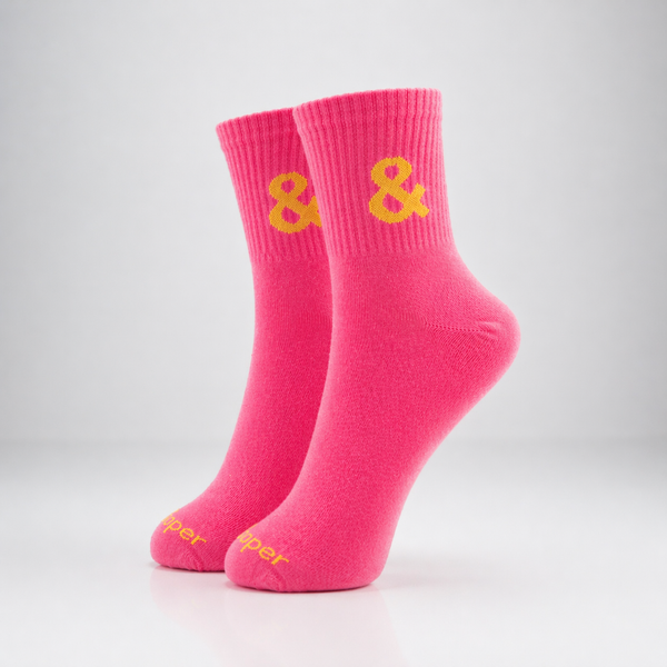 Pair of pink socks with yellow ampersand symbol on a light gray background