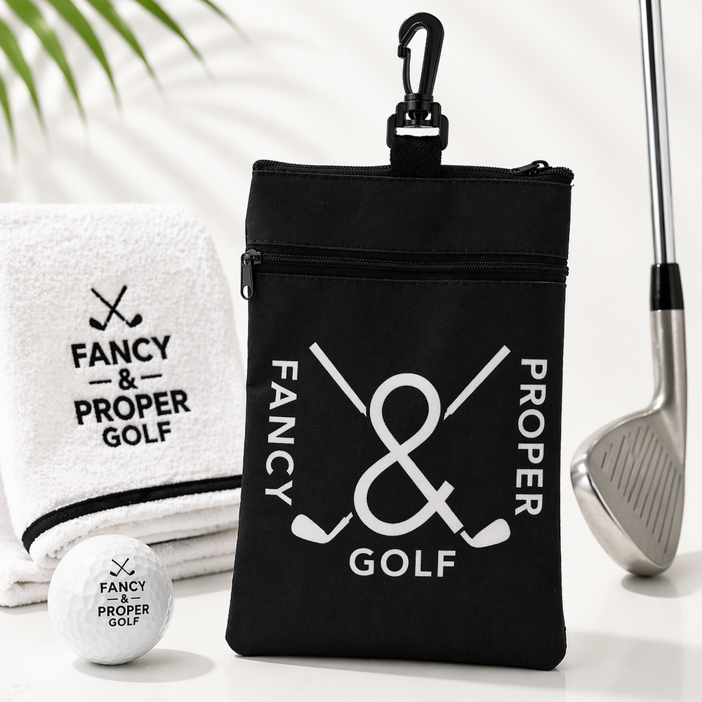 Black golf bag with 'Fancy & Proper Golf' branding, golf club, towel, and ball on a light background.