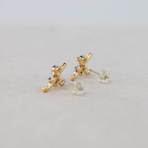 Gold earrings with clear stones on a light gray background