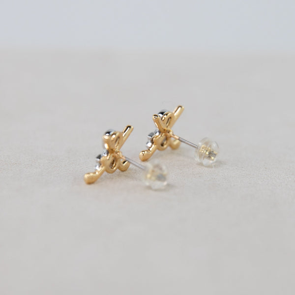 Gold earrings with clear stones on a light gray background