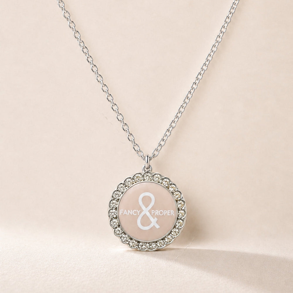 Necklace with a round pendant featuring a brand logo on a beige background