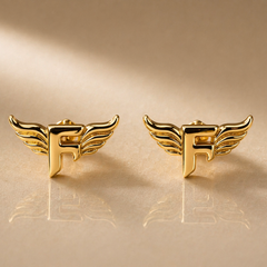 Gold winged 'F' earrings on a gold background