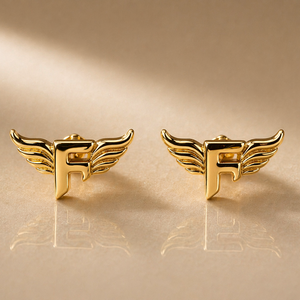 Gold winged 'F' earrings on a gold background