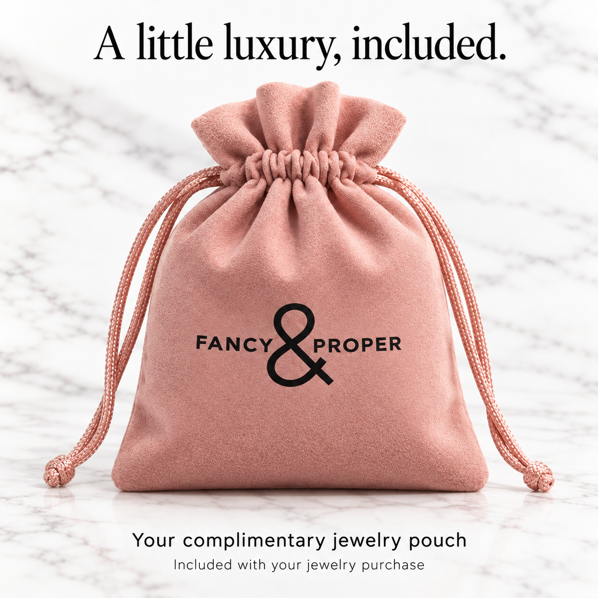 Upright blush pink Fancy & Proper complimentary jewelry pouch with black ampersand logo.