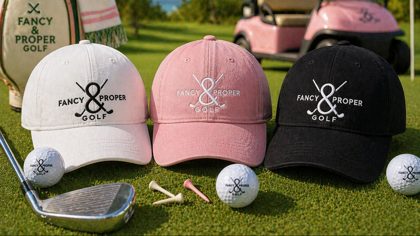 Three golf caps with 'Fancy & Proper Golf' logo on a golf course with golf balls and club.