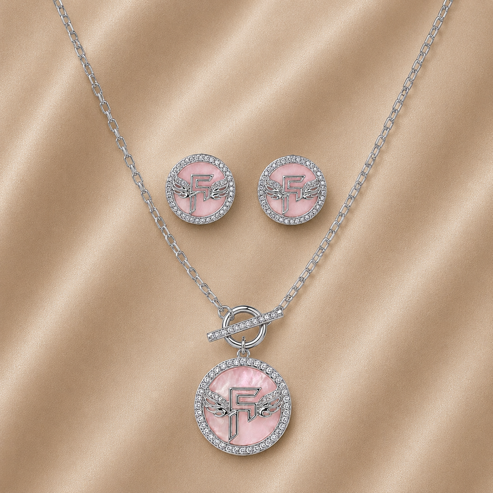 Jewelry set with pink pendant and earrings on a beige fabric background