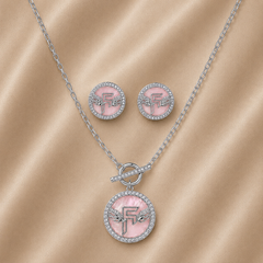 Jewelry set with pink pendant and earrings on a beige fabric background