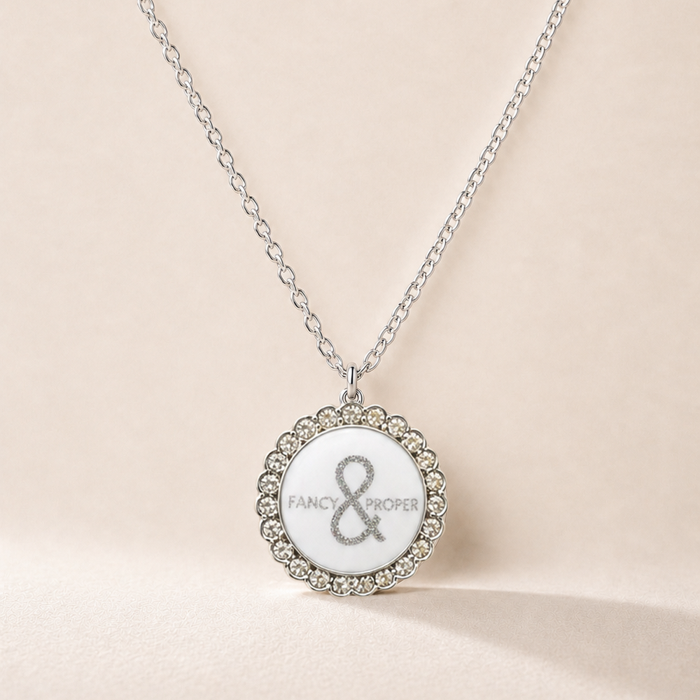 Necklace with a round pendant featuring a brand logo on a beige background